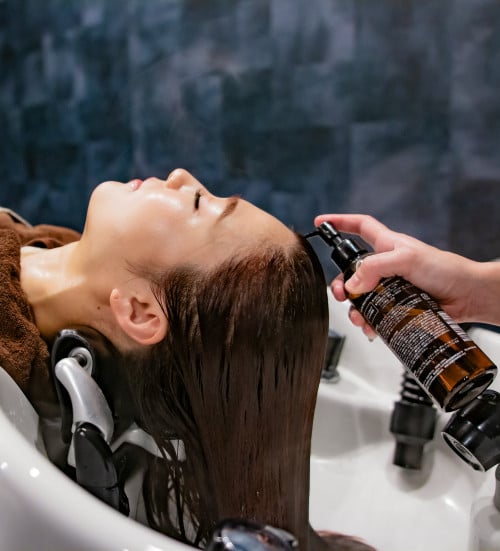 quentin-mahe-a-woman-getting-her-hair-washed-in-a-sink
