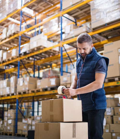 male warehouse worker sealing cardboard boxes