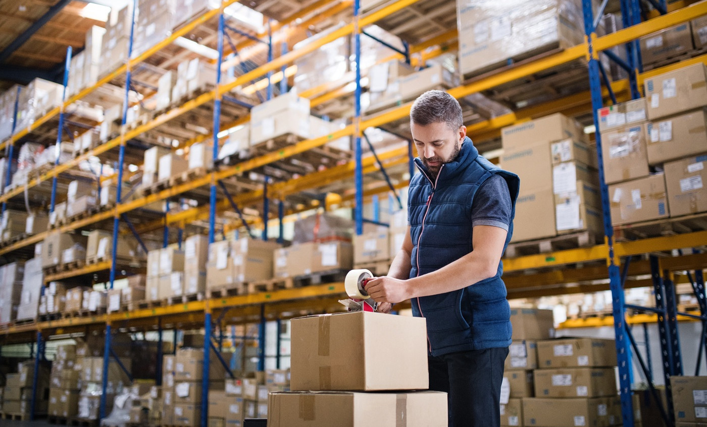 male warehouse worker sealing cardboard boxes