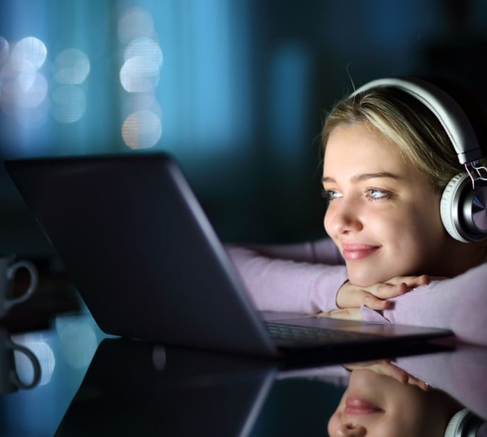 satisfied teen wearing headphones watching media