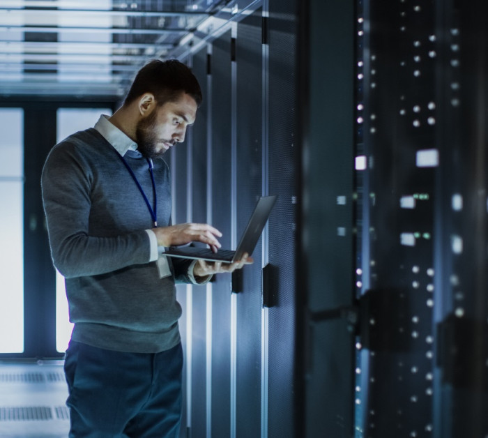 technician works on laptop next server