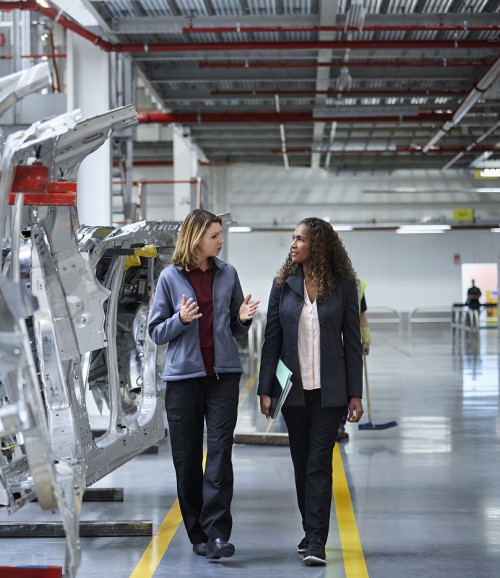 engineers walking while discussing by car chassis