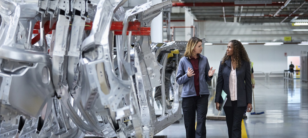 engineers walking while discussing by car chassis