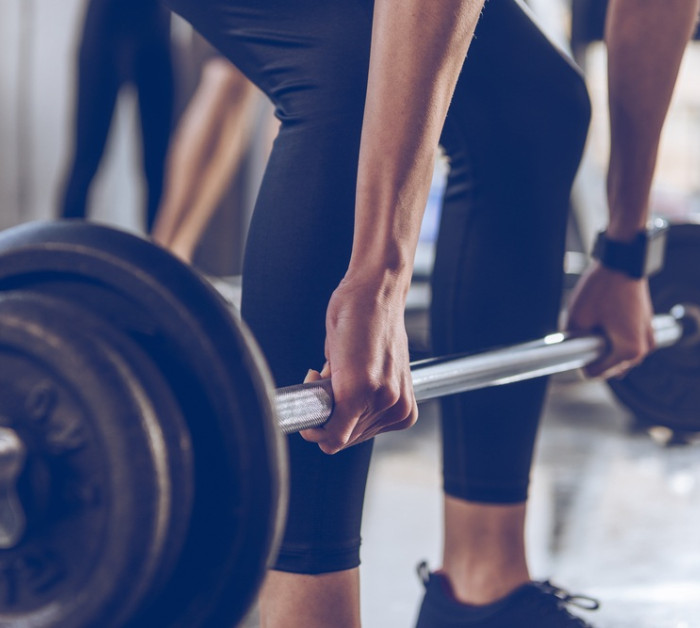 close partial view sportswoman lifting barbell