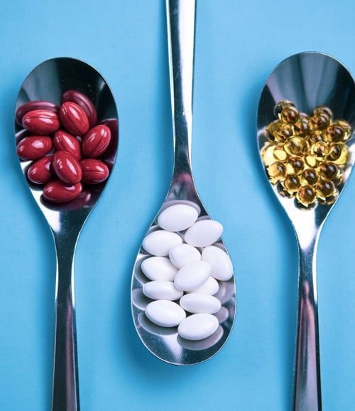 spoons pills on light blue background
