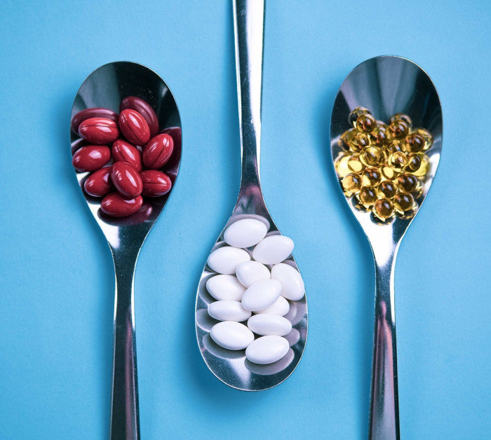 spoons pills on light blue background