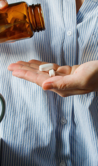 woman taking pills small brown glass
