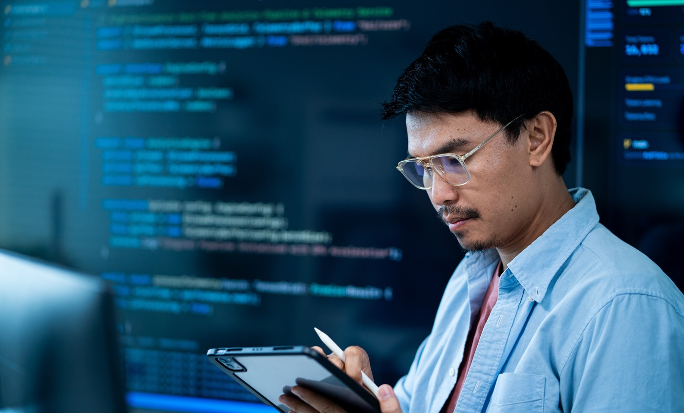 asian male software developer works multiple computers